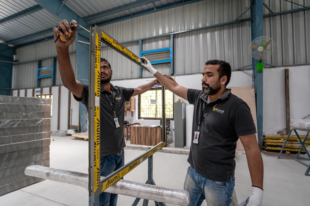 Two workshop team members measuring an aluminium frame